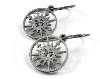 May include: A pair of silver compass earrings with a circular design featuring a compass rose with the directions N, S, E, and W. The earrings have a hoop design.