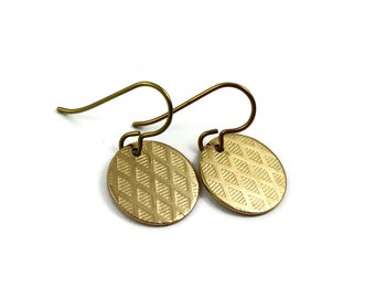 May include: A pair of gold-toned earrings with a geometric pattern. The earrings are made of metal and have a hook closure.