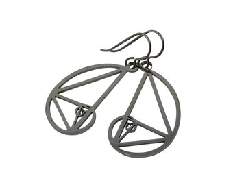 May include: A pair of dark gray metal earrings. Each earring features a geometric design with a spiral and triangular shapes. The earrings have a hook closure for pierced ears.