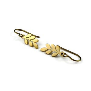 May include: A pair of gold leaf-shaped earrings with a simple design. The earrings are made of metal and have a brushed finish.