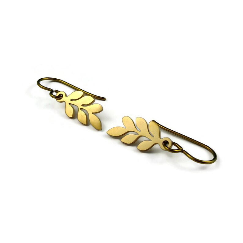 May include: A pair of gold leaf-shaped earrings with a simple design. The earrings are made of metal and have a brushed finish.