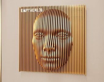 May include: A gold-coloured, three-dimensional wall art piece depicting a human face, with the text "EMPYREAL.COM" in the upper left corner. The artwork is mounted on a light grey wall. Decorative gold-coloured spheres and tables are in the foreground.