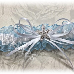 May include: A white satin and light blue tulle garter with a rhinestone starfish embellishment.