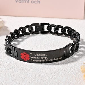 Puede incluir: Pulsera de alerta médica negra con un diseño de eslabones de cadena. La pulsera presenta un símbolo médico rojo y el texto: Diabetes T1, Bomba de insulina, Marcapasos/Anticoagulante.