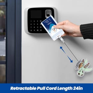 May include: A white retractable badge holder with a 24-inch pull cord. The badge holder is being used to access a security system. A cartoon turtle charm is attached to the cord. The text "DUUUUUDE" is on the charm.