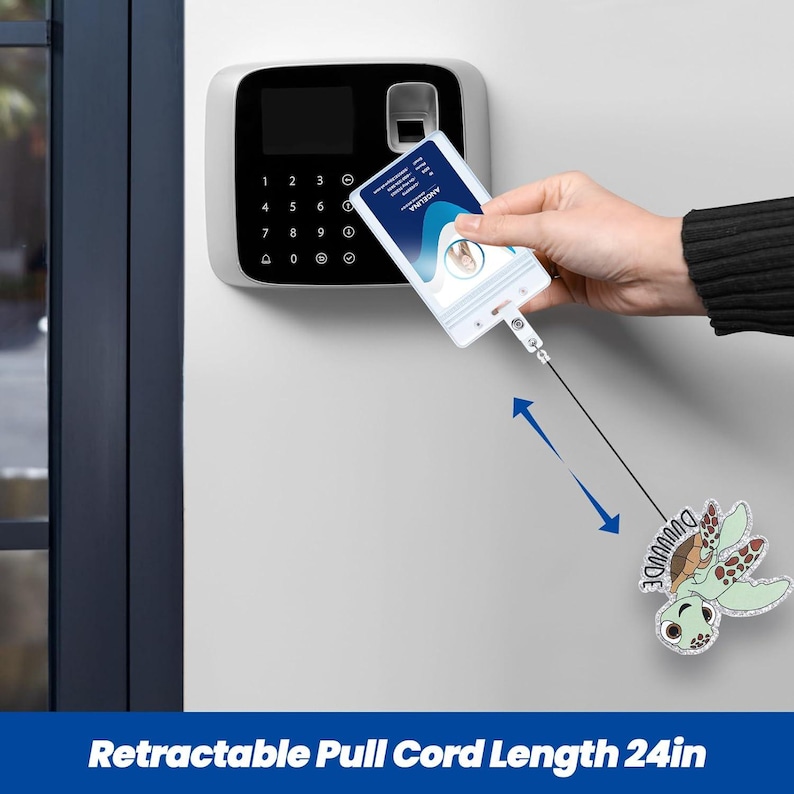 May include: A white retractable badge holder with a 24-inch pull cord. The badge holder is being used to access a security system. A cartoon turtle charm is attached to the cord. The text "DUUUUUDE" is on the charm.
