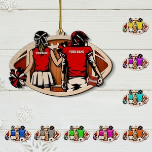 Könnte beinhalten: Holzschmuck im Football-Design mit einem Spieler und einem Cheerleader in roten Uniformen. Der Text "YOUR NAME" steht auf den Trikots. Weitere Ornamente mit verschiedenen Farbschemata sind ebenfalls sichtbar.