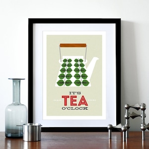May include: A framed print with a white teapot with green leaves on it. The text "It's Tea O'Clock" is below the teapot.