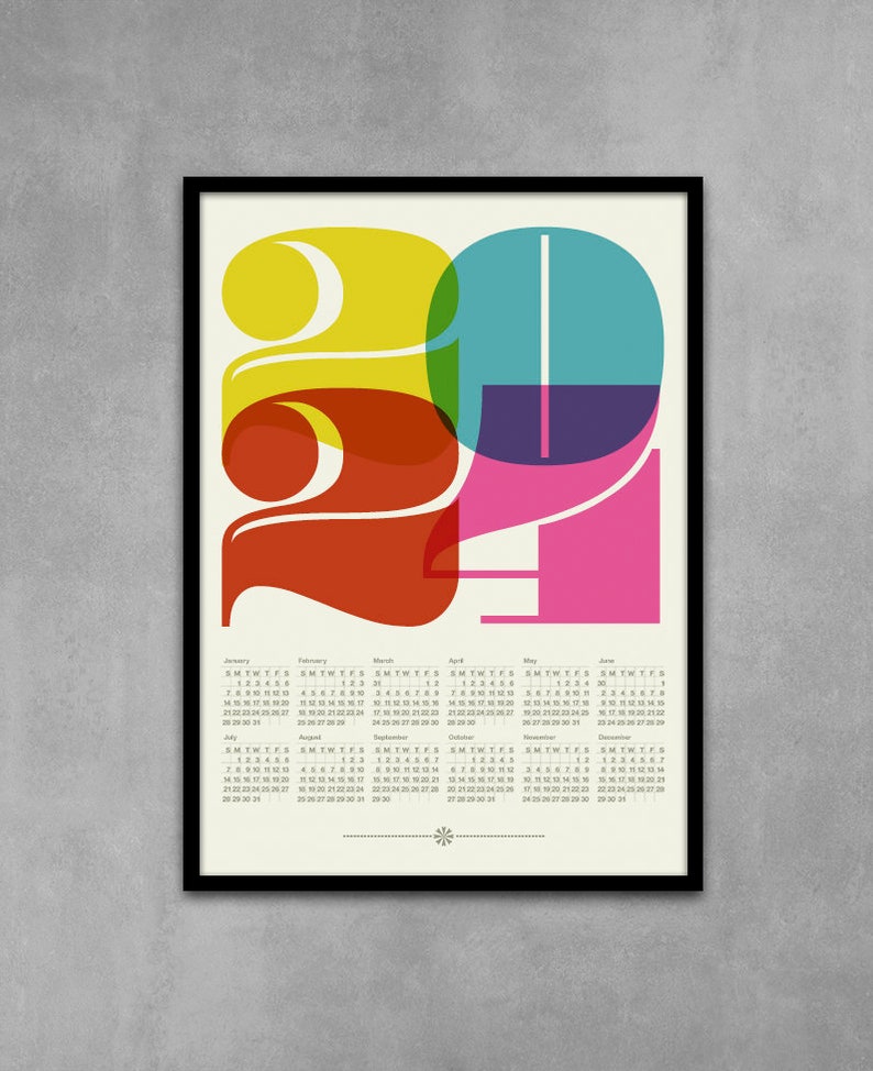 May include: A colorful calendar for the year 2021 with a graphic design of the numbers 2021 in overlapping circles of yellow, red, teal, purple, and pink. The calendar includes all 12 months of the year.