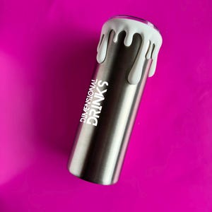 May include: A stainless steel tumbler with white dripped paint effect around the rim. The text "DIMENSIONAL DRINKS" is printed vertically in white on the side of the tumbler. The background is a solid magenta color.