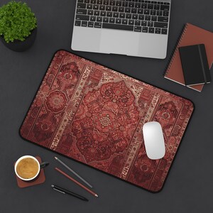 May include: A red and gold patterned mousepad with a white mouse on top. The mousepad has a traditional Persian rug design.