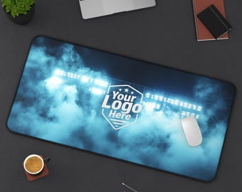 Peut inclure: Tapis de souris rectangulaire avec une scène de stade, des lumières vives et un fond bleu nuageux. Le tapis de souris porte le texte "Your Logo Here" dans un design de bouclier blanc. Une souris blanche est posée dessus.