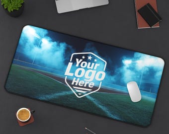 Peut inclure: Tapis de souris rectangulaire avec un motif de terrain de baseball et le texte "Your Logo Here" dans un bouclier blanc. Le tapis a une bordure noire et une souris blanche est à droite. Un ordinateur portable, une tasse à café et un bloc-notes sont également visibles.
