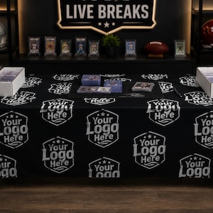 Pode incluir: Uma toalha de mesa retangular preta com um padrão repetitivo de logótipos brancos em forma de escudo com o texto Your Logo Here. A toalha cobre uma mesa com caixas de armazenamento brancas cheias de cartas e pilhas de cartas.