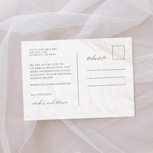 Puede incluir: Una tarjeta postal de anuncio de boda blanca con un fondo de papel texturizado. El texto dice "The Future Mr. & Mrs. 128 Love Lane Plymouth, MA 02164 We are so excited to celebrate with you! For more information please navigate to our wedding website below: www.zola.com/hannigan All our love, Amber and Brian Deliver to"