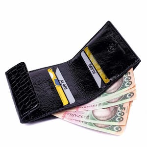 Black leather wallet with a crocodile texture on the flap. The wallet is open, revealing several credit cards and  banknotes.