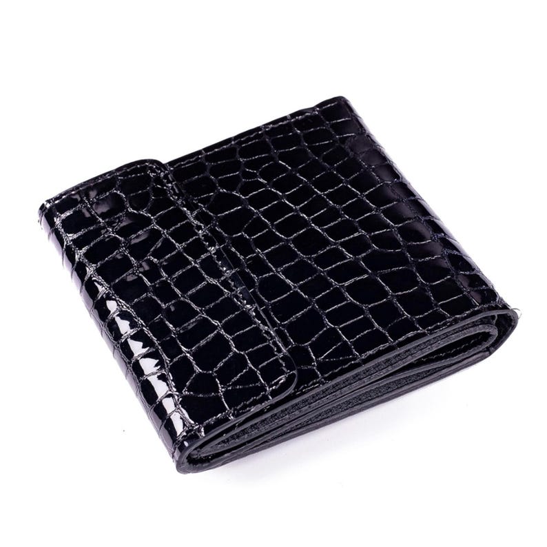 A black, glossy wallet with a crocodile skin texture. The wallet is folded and has a snap closure. The surface reflects light, highlighting the texture and shape of the wallet. The wallet to made of leather.