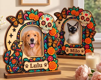 May include: Two wooden picture frames featuring colorful Day of the Dead motifs, including sugar skulls, orange butterflies, and marigold flowers. One frame displays a golden retriever and the name Lulu, while the other shows a cat and the name Milo.