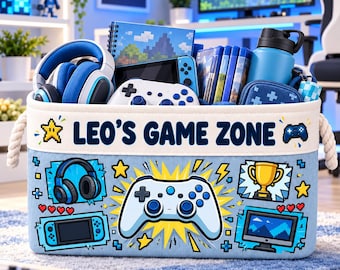 Peut inclure: Un bac de rangement en tissu bleu clair avec des poignées en corde, portant l'inscription LEO'S GAME ZONE et des graphismes de manette, casque, trophée et console portable. Le bac contient des accessoires de jeu, dont un casque et une gourde.