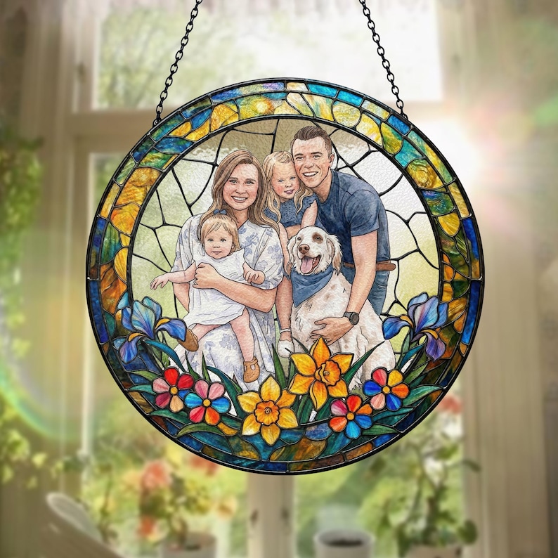 May include: A round stained glass window featuring a family portrait with a dog, surrounded by colorful flowers. The glass has a black border and is suspended by a chain. The artwork showcases a vibrant display of colors.