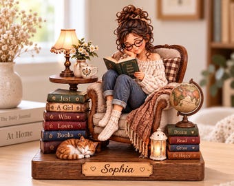 May include: A figurine of a person with brown hair and glasses sitting in a chair reading a book. The base features the name Sophia, stacks of books labeled Just A Girl Who Loves Books and Dream Read Grow Be Happy, a sleeping cat, and a globe.