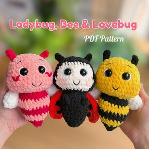 Może przedstawiać: Trzy szydełkowe pluszowe zabawki: różowa biedronka, czarno-czerwona biedronka i żółto-czarna pszczoła. Zabawki mają duże, wyraziste oczy i są trzymane w dłoniach osoby. Tekst "Ladybug, Bee & Lovebug PDF Pattern" znajduje się na górze.