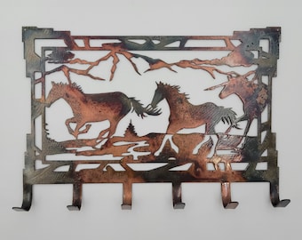 May include: A metal key rack with a rustic design featuring three horses running through a mountain landscape. The rack has five hooks for hanging keys.