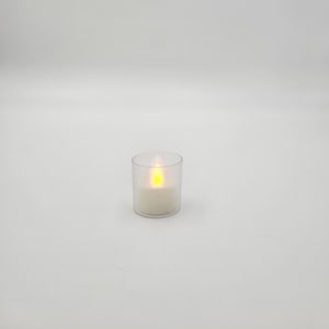 May include: A clear glass votive candle holder with a white LED tea light inside. The candle is lit and emitting a warm yellow glow.
