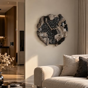 May include: A wall clock with an irregular, organic shape featuring a black and gray marbled border. The center is filled with black, textured, glittery material. It has gold-colored hands and silver Roman numerals applied to the surface.