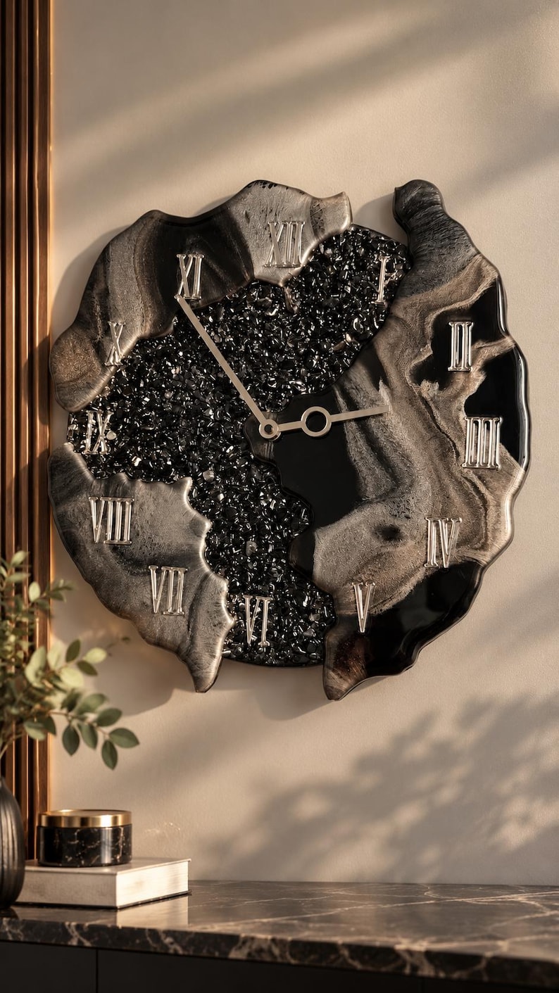 May include: A wall clock with an irregular, organic shape featuring a black and silver marbled resin finish. The center is filled with black crushed glass, and the face displays silver Roman numerals from I to XII with thin silver clock hands.