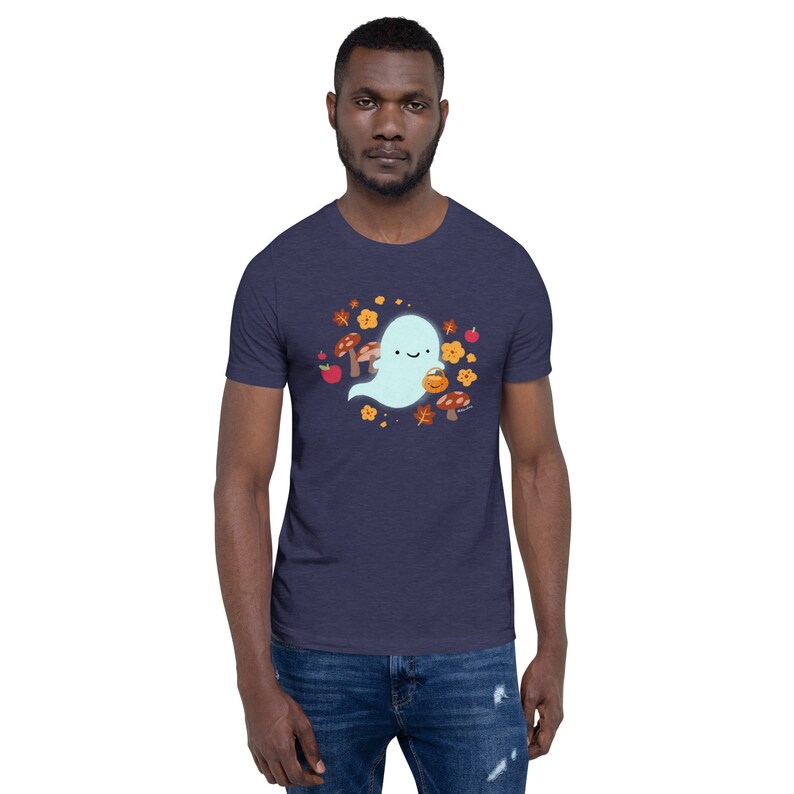 Pu&ograve; includere: Una maglietta blu navy con un simpatico fantasma che indossa un secchiello di zucca e circondato da foglie autunnali, funghi e mele.
