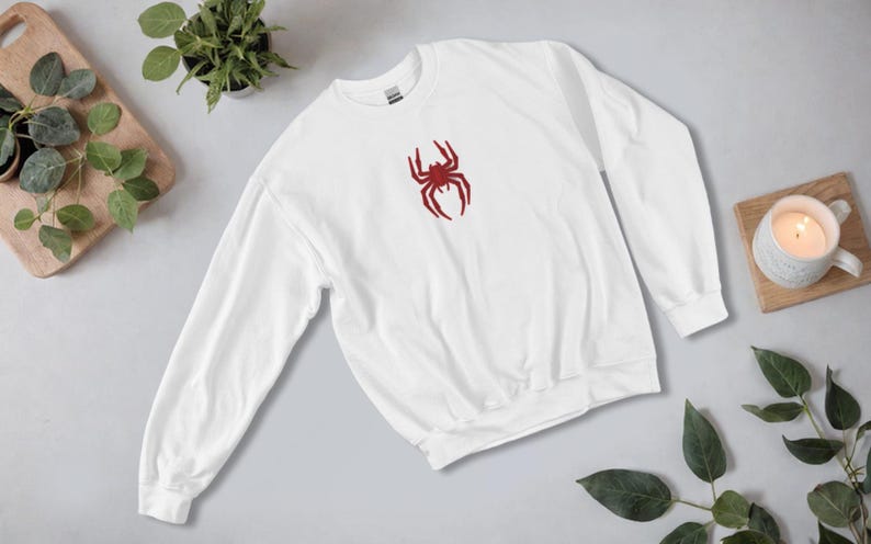May include: White sweatshirt with a red spider graphic on the front.