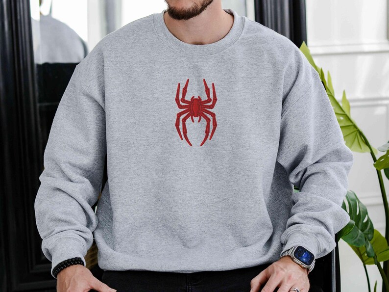 May include: A grey sweatshirt with a red spider graphic on the front.