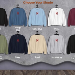 May include: Ten different colour sweatshirts with a red spider graphic on the front. The colours are black, indigo blue, light blue, white, maroon, military green, navy, sand, sport grey, and no embroidery.