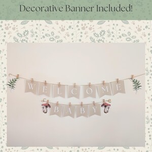 Peut inclure: Une guirlande sur le th&egrave;me de la for&ecirc;t avec les mots "WELCOME BABY" &eacute;pel&eacute;s sur des fanions beiges individuels. Les fanions sont suspendus &agrave; une ficelle et maintenus par de petites pinces &agrave; linge en bois. Des accents de foug&egrave;res et de champignons sont inclus. Le fond est neutre.