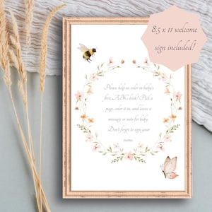 May include: A framed 8.5 x 11 welcome sign with a floral wreath and watercolor illustrations of a bee and butterfly. The sign includes text that reads, "Please help us color in baby's first ABC book!" and invites guests to leave a message.