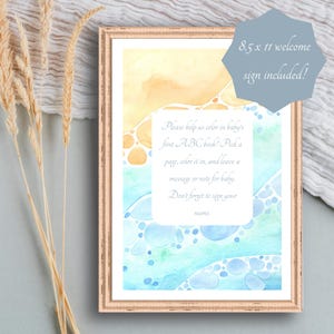 May include: A framed watercolor print with a light brown frame. The artwork features a colorful abstract design in shades of yellow, blue, and green. Text on the print reads, "Please help us color in baby's first ABC book!" and "8.5 x 11 welcome sign included!"
