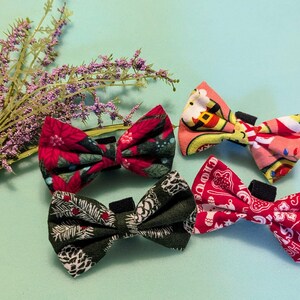 May include: Four festive bow ties with different holiday-themed patterns. The bow ties are made of fabric and have a red, green, and white color scheme.