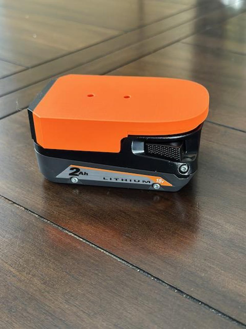 May include: An orange and black power tool battery with the text "2Ah LITHIUM 18V" printed on the side.