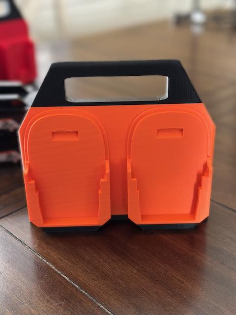 Pode incluir: Esta&ccedil;&atilde;o de carregamento impressa em 3D laranja e preta com duas ranhuras para carregar dispositivos.