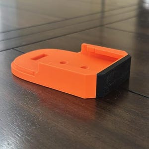 May include: Orange and black 3D printed battery holder.