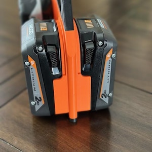 Pode incluir: Uma bateria de ferramenta el&eacute;trica preta e laranja com o texto "RIGID" e "18V LITHIUM 2Ah" impresso no lado.
