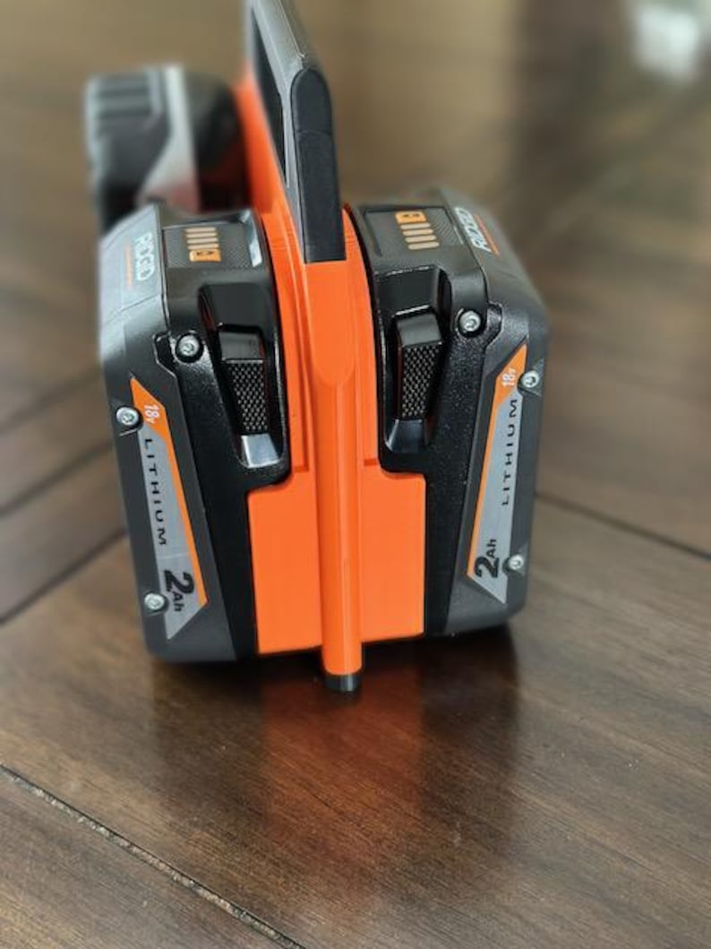 Pode incluir: Uma bateria de ferramenta el&eacute;trica preta e laranja com o texto "RIGID" e "18V LITHIUM 2Ah" impresso no lado.