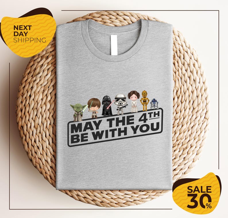 A gray t-shirt with a graphic design featuring characters from the Star Wars franchise, along with the text "May the 4th be with you".