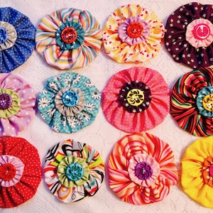 May include: Twelve fabric flowers with different patterns and colors. Each flower has a button in the center.