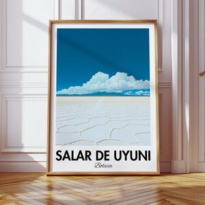 Op de afbeelding: Een ingelijste poster met een foto van de Salar de Uyuni zoutvlakte in Bolivia. De foto toont een uitgestrekt wit landschap met een blauwe lucht en witte wolken. De poster heeft de tekst "Salar de Uyuni" en "Bolivia" erop gedrukt.