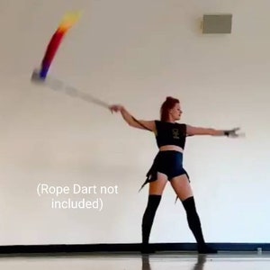 May include: A black two-piece outfit consisting of a sleeveless crop top and high-waisted shorts, paired with black over-the-knee socks. The text (Rope Dart not included) is visible on the left side. The outfit is worn during a performance.