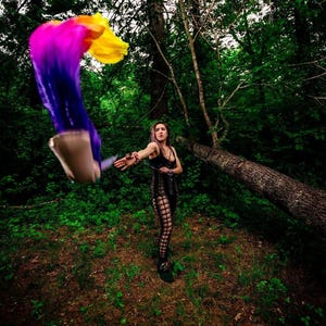 May include: A black sleeveless top and matching leggings featuring a cut-out lattice design. A set of flowing silk poi with a vibrant gradient of purple, pink, orange, and yellow is being swung through the air, creating a blurred motion effect.