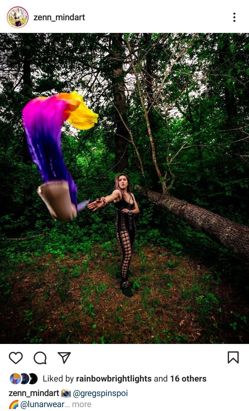 May include: A black sleeveless top and matching leggings featuring a cut-out lattice design. A set of flowing silk poi with a vibrant gradient of purple, pink, orange, and yellow is being swung through the air, creating a blurred motion effect.