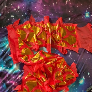 May include: A long, flexible dragon dance prop featuring a metallic gold body with red fabric accents. The structure consists of segmented, reflective gold panels framed by bright red borders, creating a vibrant, articulated appearance.